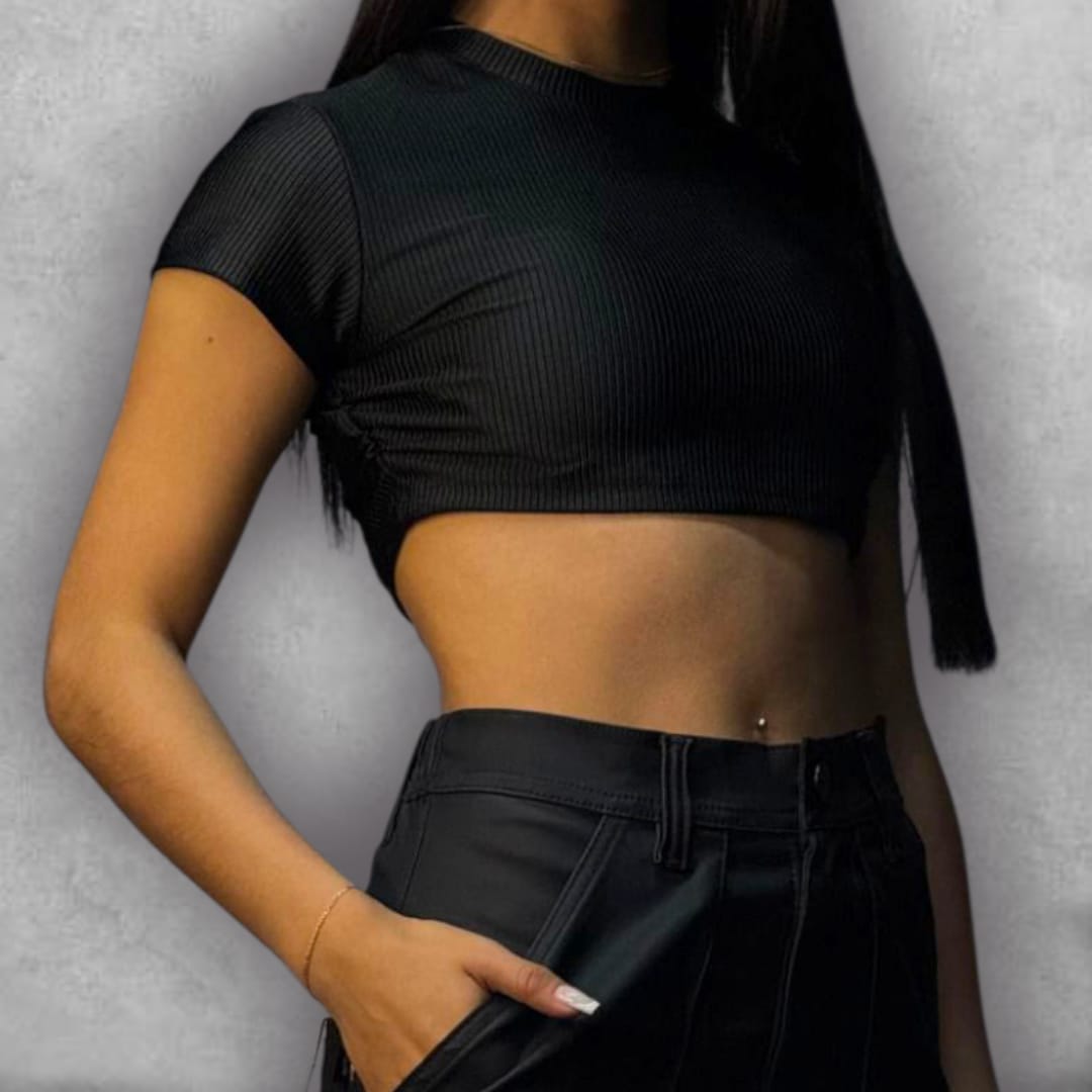 Añade un toque de textura y elegancia a tus básicos con el Croptop Clamford – Black Ribbed Edition. El tejido elástico acanalado no solo es cómodo, sino que le da una dimensión visual al negro. El diseño crop y la manga corta lo hacen perfecto para el clima cálido o para un look de capas, mientras que el cuello alto asegura un acabado pulido. Es la elección ideal para quienes buscan un top moderno, versátil y que nunca pasa de moda.