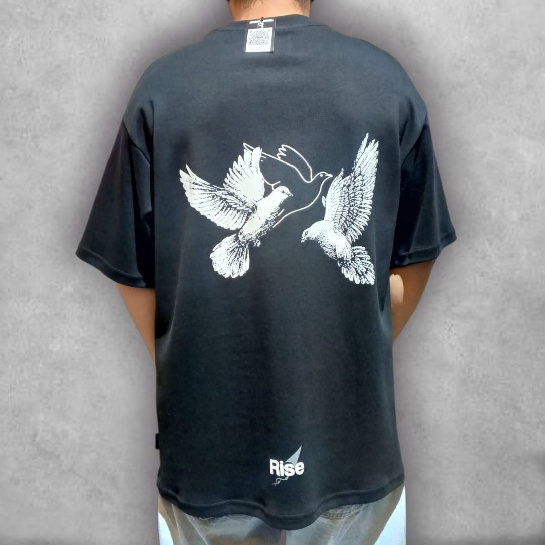 Consigue la ligereza del estilo con la Camiseta Oversize Rise – Freedom Flight Edition. Esta prenda negra de ajuste oversize es el lienzo perfecto para el gráfico minimalista de dos palomas, que representa la conexión y el movimiento ascendente. Es la camiseta ideal para un look relajado, ofreciendo una comodidad superior sin renunciar a un diseño que comunica tranquilidad y propósito. Una pieza esencial para elevar tus básicos urbanos.