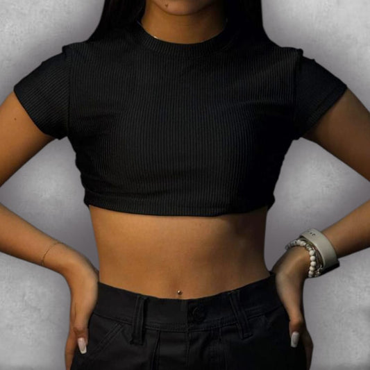 Añade un toque de textura y elegancia a tus básicos con el Croptop Clamford – Black Ribbed Edition. El tejido elástico acanalado no solo es cómodo, sino que le da una dimensión visual al negro. El diseño crop y la manga corta lo hacen perfecto para el clima cálido o para un look de capas, mientras que el cuello alto asegura un acabado pulido. Es la elección ideal para quienes buscan un top moderno, versátil y que nunca pasa de moda.