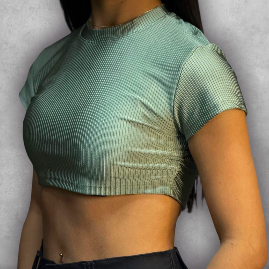 Añade un toque de tendencia a tus básicos con el Croptop Clamford – Mint Ribbed Edition. El tejido elástico acanalado no solo es increíblemente cómodo, sino que le da una textura visualmente rica a su color verde claro. El diseño crop y la manga corta lo hacen perfecto para el clima cálido, mientras que el cuello alto asegura un look pulido y versátil. Es la elección ideal para un estilo urbano que busca la comodidad sin sacrificar la sofisticación.
