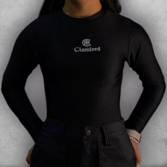 Consigue un look chic y atemporal con el Body Clamford – Midnight Ribbed Edition. El tejido elástico acanalado no solo es increíblemente cómodo, sino que le da una textura rica al color negro. Su diseño de manga larga y cuello alto lo hace perfecto para cualquier estación. El discreto bordado del logo de Clamford en el pecho sella la prenda con un aire de alta costura, siendo la elección ideal para un fondo de armario que requiere elegancia sin esfuerzo.