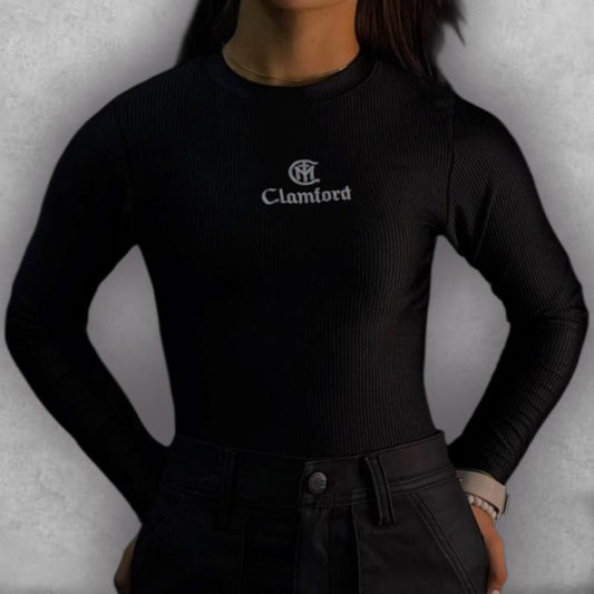 Consigue un look chic y atemporal con el Body Clamford – Midnight Ribbed Edition. El tejido elástico acanalado no solo es increíblemente cómodo, sino que le da una textura rica al color negro. Su diseño de manga larga y cuello alto lo hace perfecto para cualquier estación. El discreto bordado del logo de Clamford en el pecho sella la prenda con un aire de alta costura, siendo la elección ideal para un fondo de armario que requiere elegancia sin esfuerzo.