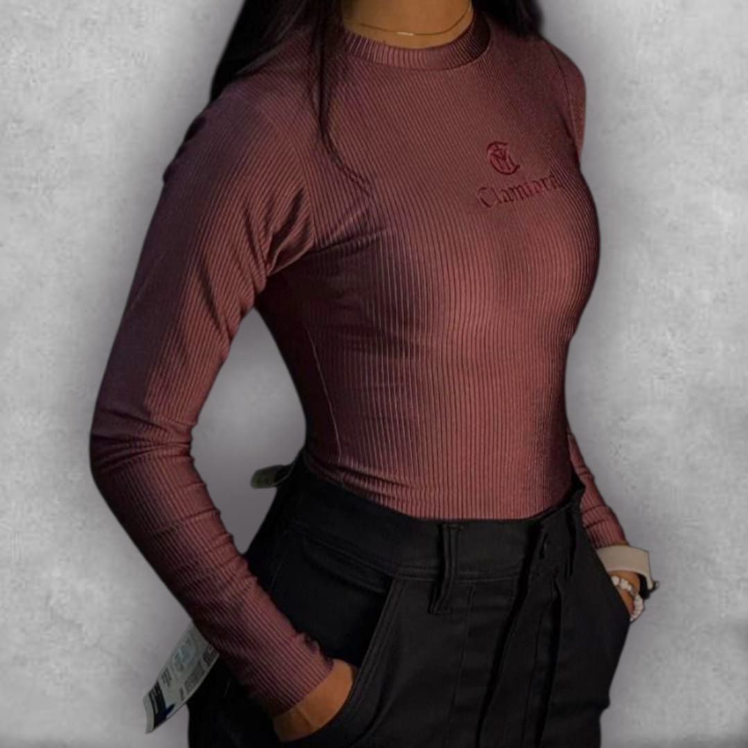 Descubre la versatilidad con el Body Clamford – Ribbed Elegance Edition. Su tejido elástico acanalado no solo es cómodo, sino que crea una textura visualmente rica en su hermoso color vino. El diseño de manga larga y cuello alto proporciona una cobertura elegante y es perfecto para transicionar entre estaciones. El bordado frontal minimalista de Clamford asegura un estilo pulido y chic. Es la pieza imprescindible para lograr un look de tendencia sin esfuerzo, pasando de casual a formal con los accesorios co